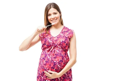 smiling pregnant woman brushing teeth